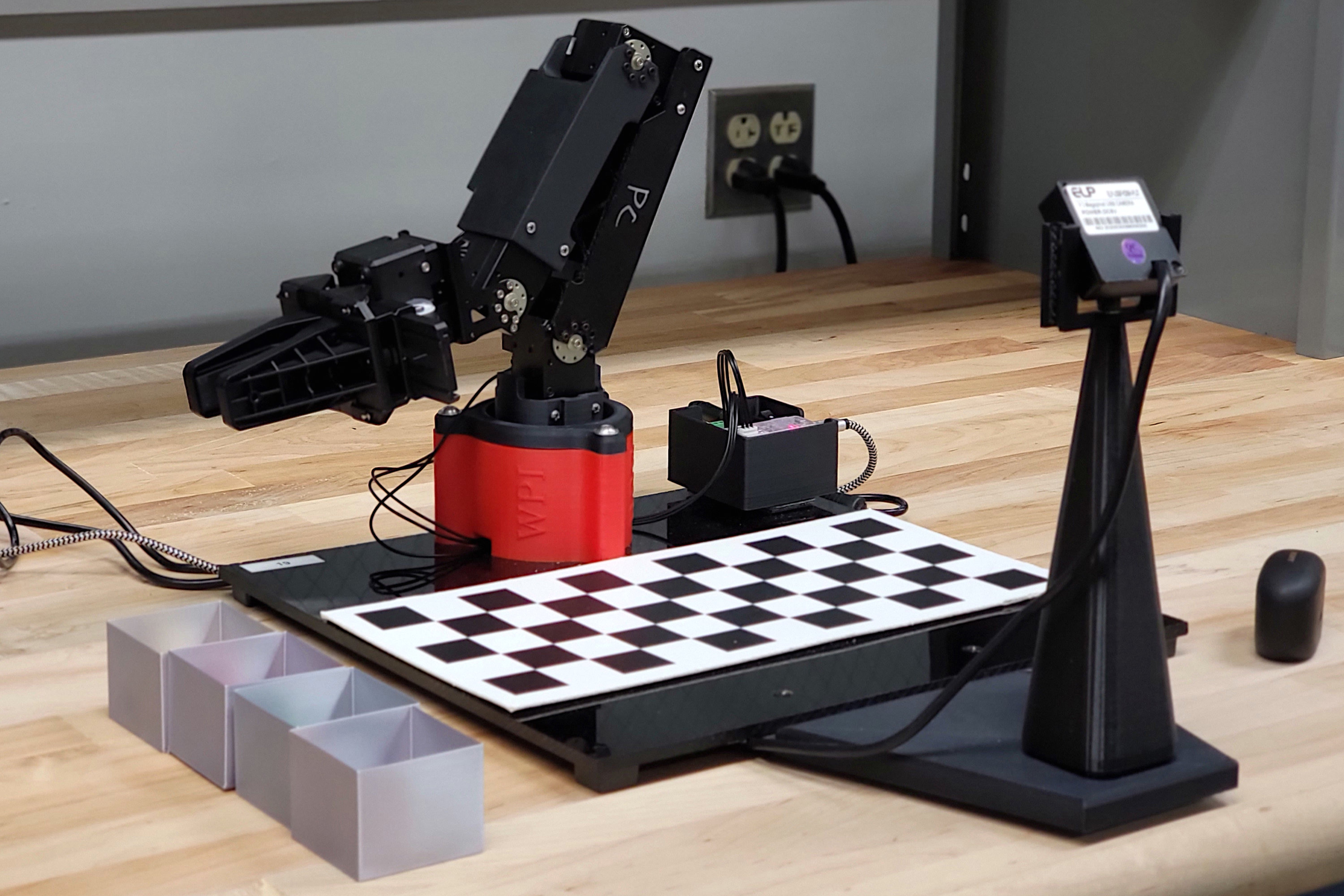Our 4-DOF OpenManipulator-X arm, checkerboard, and
camera setup